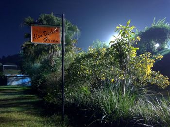 Road sign by trees against sky