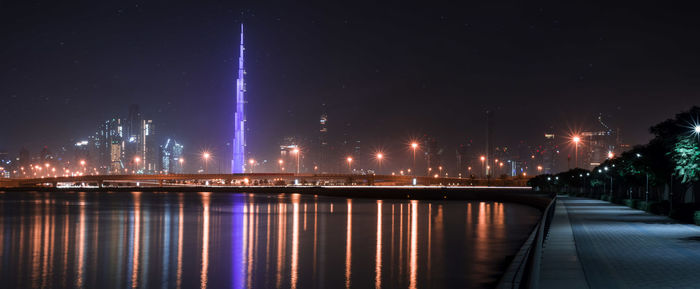 Illuminated bridge over river in city at night