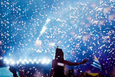 Woman standing amidst confetti at concert