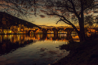 Arch bridge over river against sky during sunset