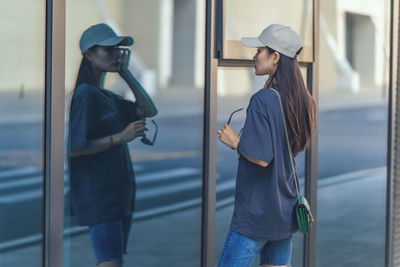 Woman admiring herself while looking at glass wall