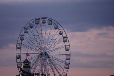 Low angle view of ferris wheel against cloudy sky