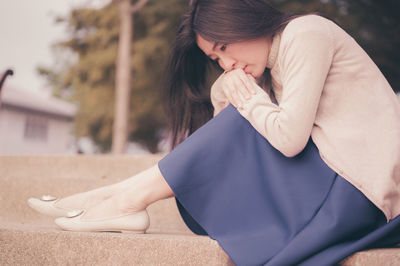 Midsection of woman sitting in park