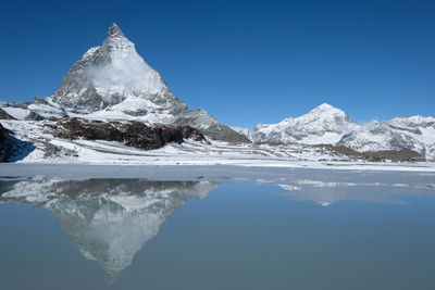Scenic view of snowcapped mountain matterhorn reflection in lake against blue sky