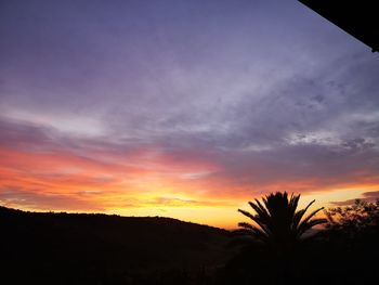 Silhouette trees on landscape against romantic sky at sunset
