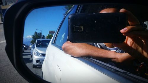 Close-up of hand on side-view mirror of car