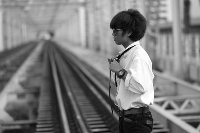 Side view of man standing on railroad track