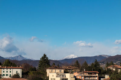 Houses by mountains against blue sky