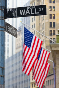 Low angle view of information sign with flags in background