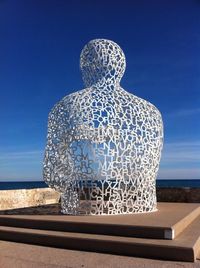 Rear view of statue on beach against clear sky