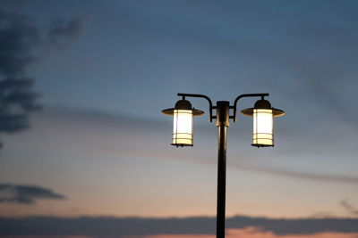 Low angle view of illuminated street light against sky