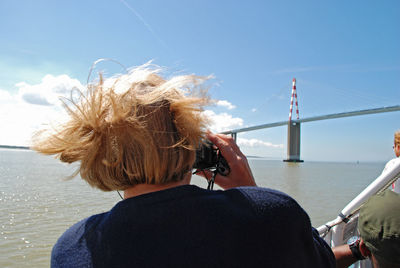 Rear view of woman photographing sea against sky