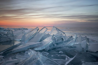 Snow covered landscape against sky during sunset