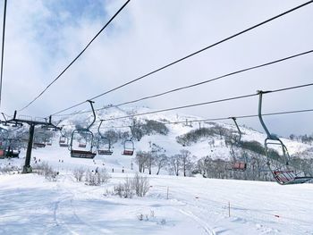 Ski lift over snow covered trees against sky