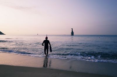 Man on beach against sky during sunset
