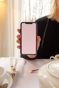 Woman hand holding modern mobile phone on light clipping path inside. white blank empty screen 