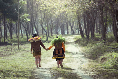 Rear view of two women walking in forest