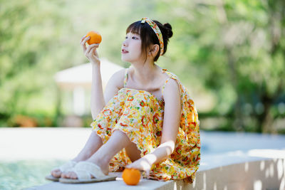 Portrait of young woman with arms raised sitting on field