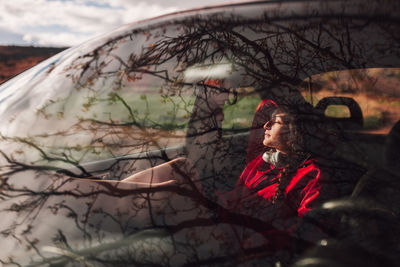 Young woman sitting in car seen through windshield