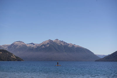 Scenic view of sea and mountains against clear blue sky