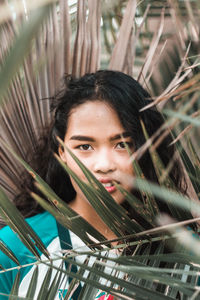 Portrait of teenage girl amidst palm leaves