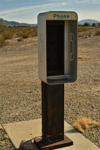 Close-up of telephone booth on field against sky