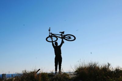Rear view of man with bicycle on field