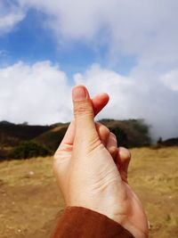 Close-up of human hand against sky