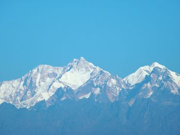 Scenic view of snow covered mountains against blue sky