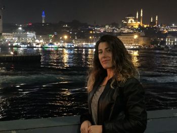 Portrait of young woman in illuminated city at night