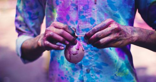 Midsection of man tying water in balloon during holi