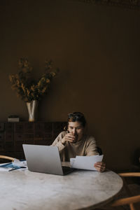 Non-binary person examining finance bills while sitting at home