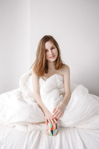 Portrait of beautiful young woman lying on bed