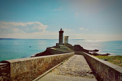 Lighthouse by sea against sky