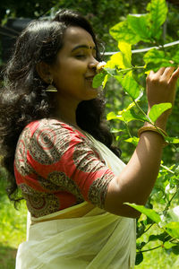 Side view of a smiling young woman holding plant