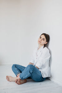 Woman sitting on floor against wall