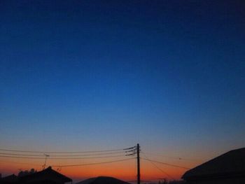 Silhouette electricity pylons against clear blue sky