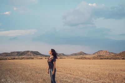 Side view of woman standing on field against sky