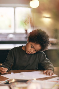 Boy with curly hair doing homework at home