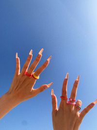 Low angle view of hands against blue sky