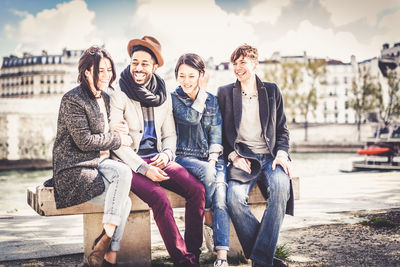 Full length of smiling young man sitting in city