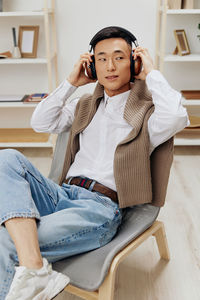 Young man wearing headphones sitting on chair