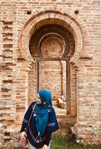 Woman wearing hijab while standing against old building