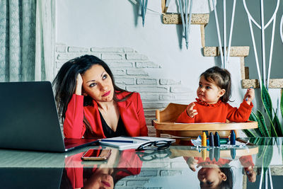 Young executive woman tired of working at home with her young daughter