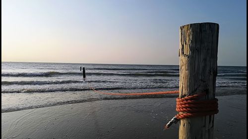 Wooden posts on beach against clear sky