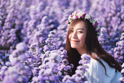 Portrait of happy woman against purple flowering plants