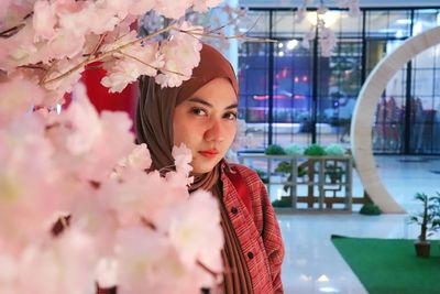 Portrait of young hijab asian woman close up with sakura flower. 