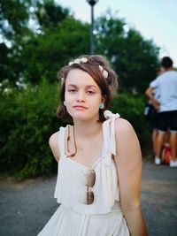 Portrait of young woman standing against plants