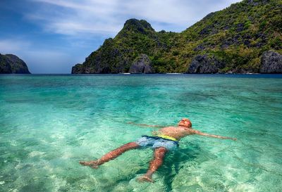 Man swimming in sea against sky