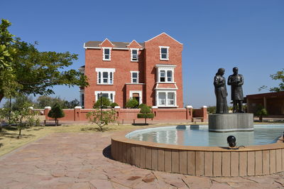 Statue amidst fountain by building against clear blue sky